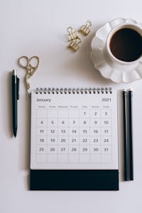 A calendar or planner with written goals and a coffee cup nearby.