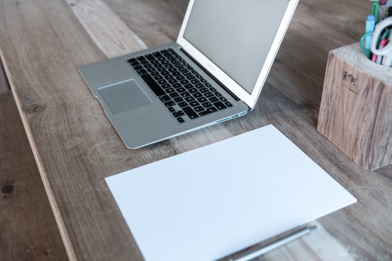 A tidy desk with a notebook, pen, and a single laptop