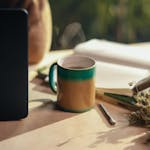 A cozy scene with a journal, pen, and a cup of tea on a wooden desk