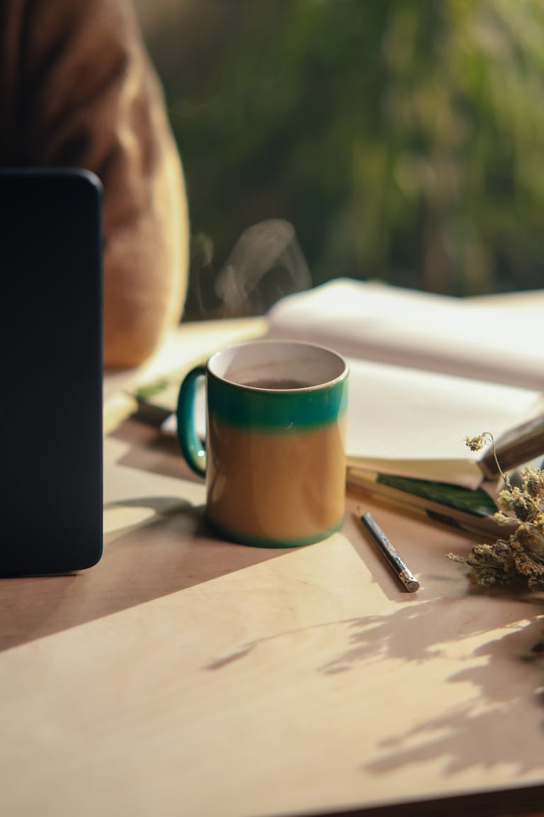 A cozy scene with a journal, pen, and a cup of tea on a wooden desk