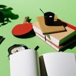 A desk overflowing with papers, a clock in the background, and a checklist highlighting one item in green.