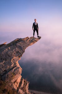 A person confidently standing at the edge of a cliff overlooking a sunrise, symbolizing courage and new beginnings.