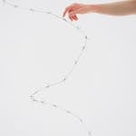 A hand gently touches barbed wire on a white background, symbolizing tension.