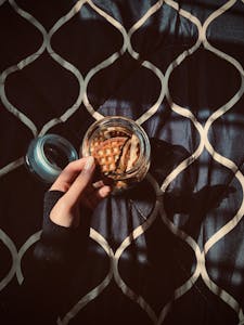 A hand struggling to reach a cookie jar placed on a high shelf