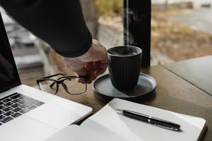 A person working at a desk with minimal distractions, surrounded by tools for focus, such as a notebook, a pen, and a cup of coffee.