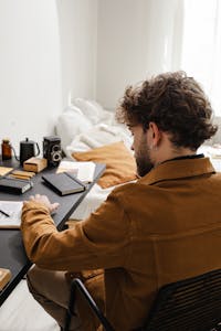 An artist or writer immersed in work, surrounded by glowing light and minimal distractions