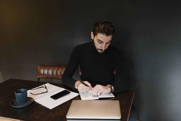 A person organizing their workspace, with a to-do list, a cup of coffee, and a calendar, symbolizing productive habits.