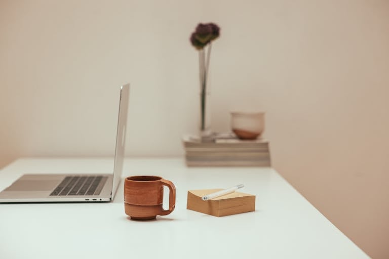 A calm workspace with just a laptop, coffee, and a notepad—symbolizing focus and simplicity.