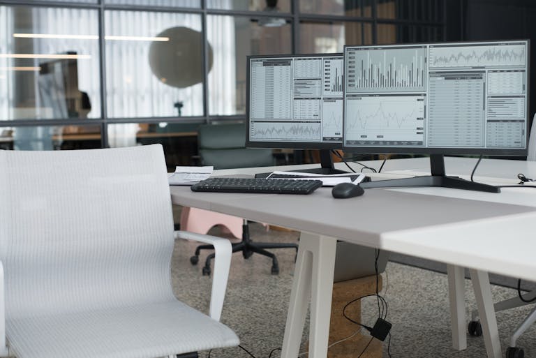 A clean, modern home office with natural light, ergonomic chair, and dual monitors.
