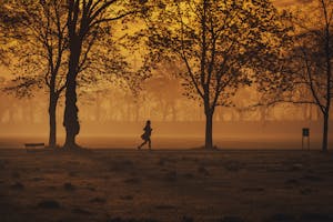 A person jogging through fog at sunrise, symbolizing persistence despite low visibility or energy.