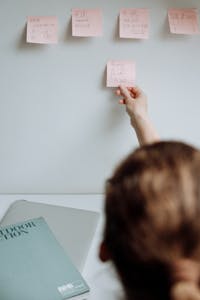 A person using sticky notes and a laptop to organize tasks.
