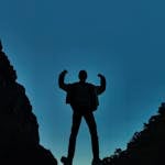 A person standing tall on a mountain peak, symbolizing strength and resilience.