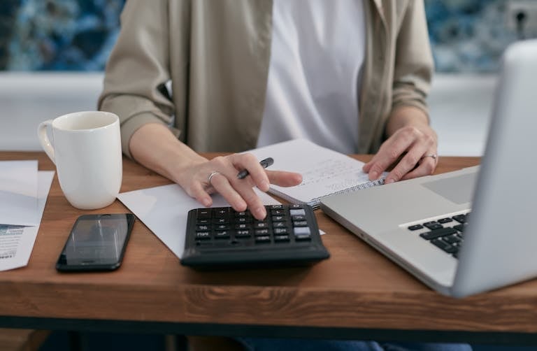 A person using a planner or digital calendar with a cup of coffee beside them