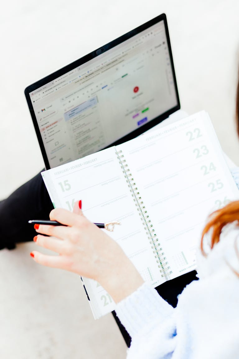 A person writing down goals in a notebook, with a focus on a calendar or a planning app.