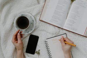 A peaceful nature scene with a smartphone powered off beside a journal and a cup of tea.
