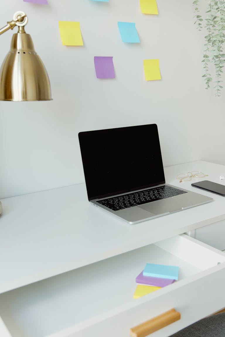 A person placing their smartphone in a drawer while working at a clean desk.