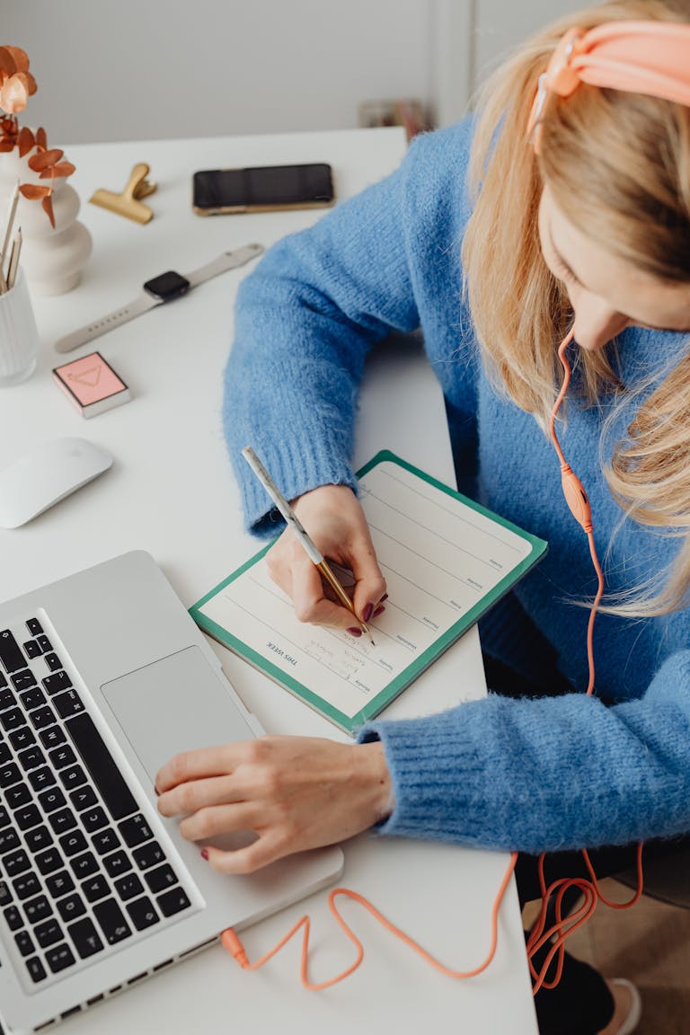 A person working at a desk with a planner, laptop, and a clock showing organized time