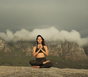 A calm person meditating on a mountain with a storm behind them, symbolizing inner peace during chaos.