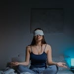 A person practicing yoga or meditating in a calm environment with soft lighting.