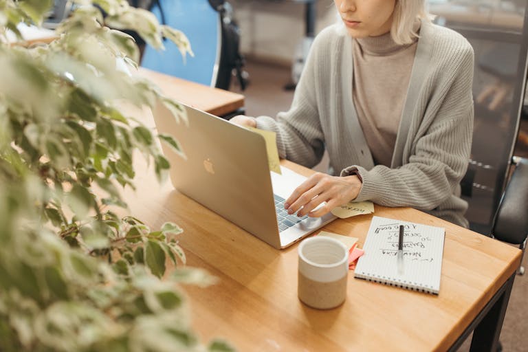 A person working at a desk surrounded by plants and books, with a calm and organized workspace.