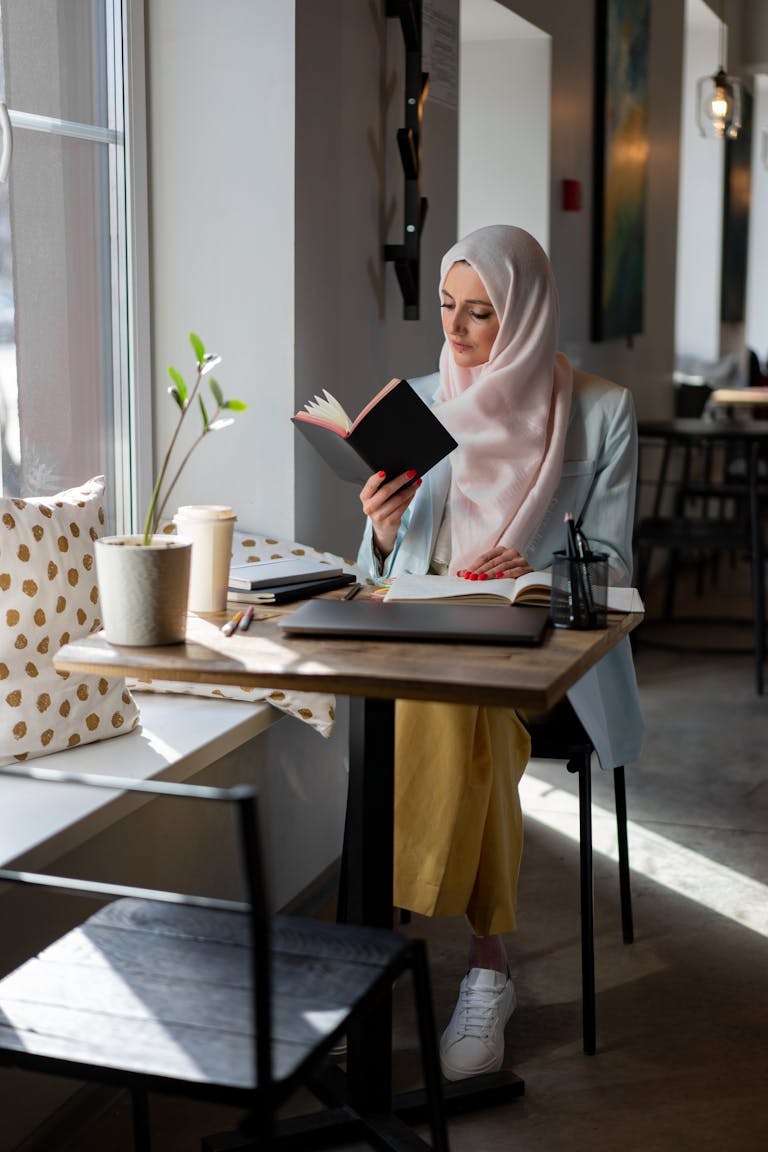A person practicing self-care, such as reading a book in a cozy setting, with a digital device turned off in the background.