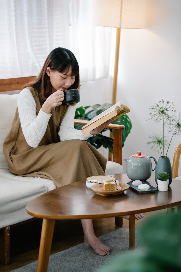 A person journaling while sipping tea, surrounded by motivational books and affirmations