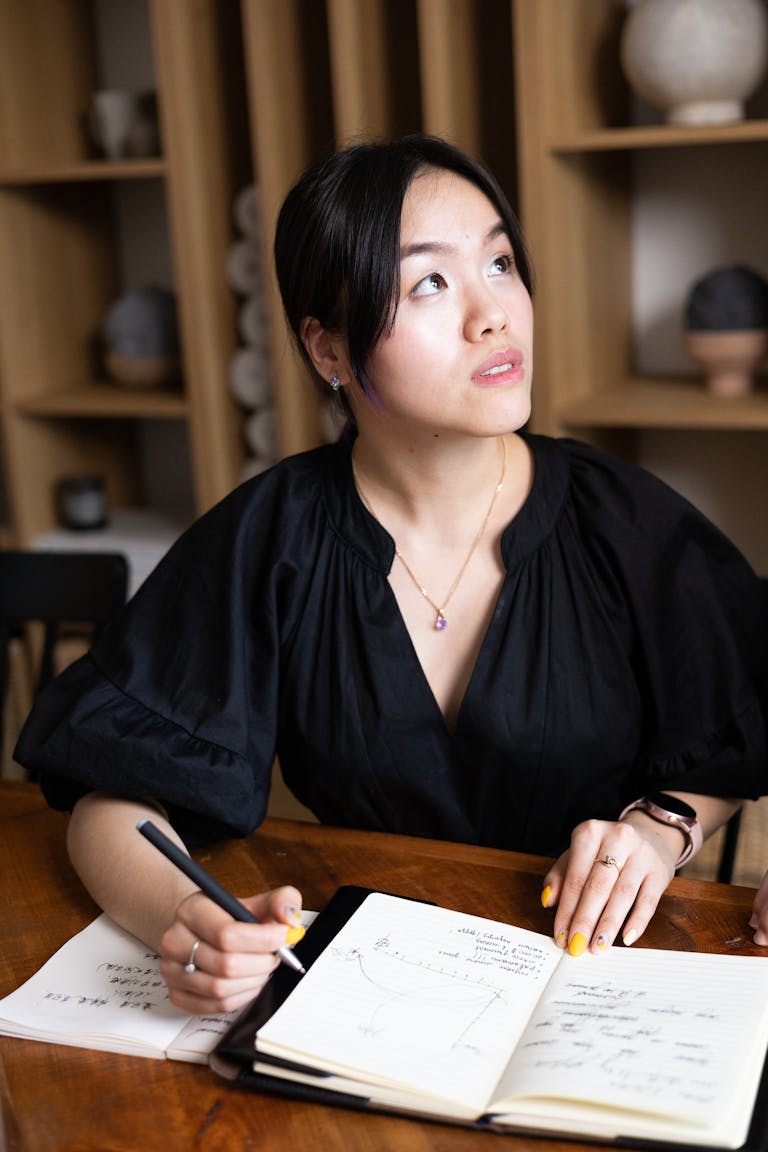 A person writing on a goal-setting notebook, with a vision board in the background