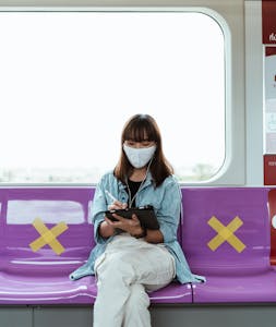 A person with headphones reading or working on a tablet during a subway ride