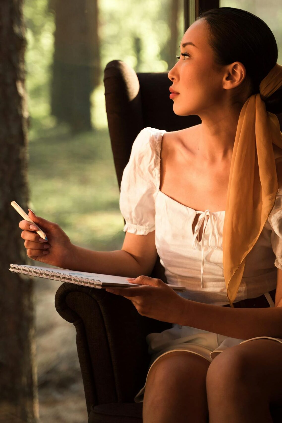A person staring peacefully out a window with a journal nearby, no devices in sight.