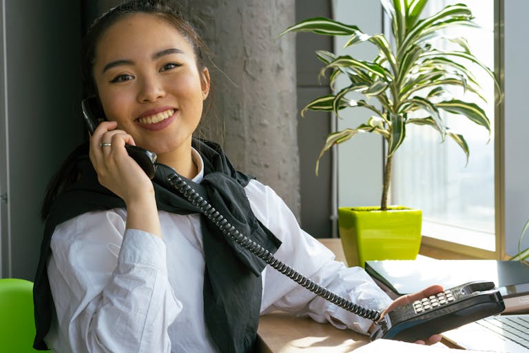 A bright office desk with a person stretching and smiling while working with natural sunlight.