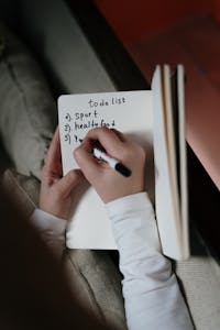 A person holding a habit tracker notebook with a pen, symbolizing goal setting and habit tracking.
