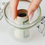 A jar labeled "Emergency Fund" filling up with coins and bills