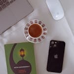 A minimalist workspace with a phone face-down, a journal, and a cup of coffee.