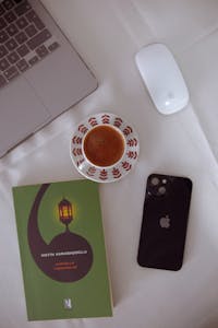 A minimalist workspace with a phone face-down, a journal, and a cup of coffee.