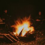 A peaceful night sky with someone sitting calmly by a campfire.