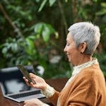 A person using technology outdoors, with nature in the background