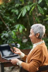 A person using technology outdoors, with nature in the background
