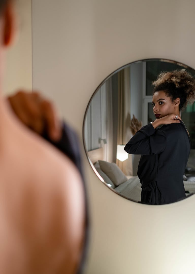 A confident person looking at their reflection in a mirror with calm assurance.