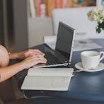 A person studying online with a laptop and coffee