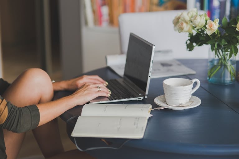 A person studying online with a laptop and coffee