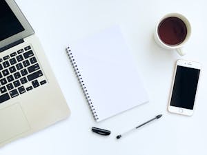  A clean smartphone home screen with just a few essential apps, lying next to a notepad and coffee cup on a minimalist desk.