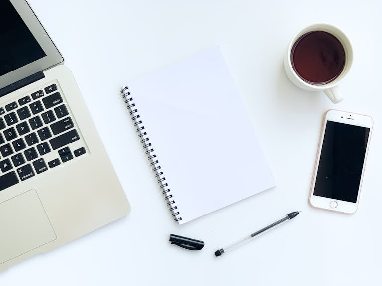 A clean smartphone home screen with just a few essential apps, lying next to a notepad and coffee cup on a minimalist desk.