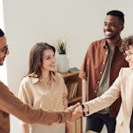 A group of professionals shaking hands at a networking event, smiling and exchanging business cards.