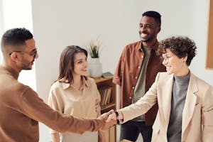 A group of professionals shaking hands at a networking event, smiling and exchanging business cards.