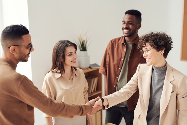 A group of professionals shaking hands at a networking event, smiling and exchanging business cards.