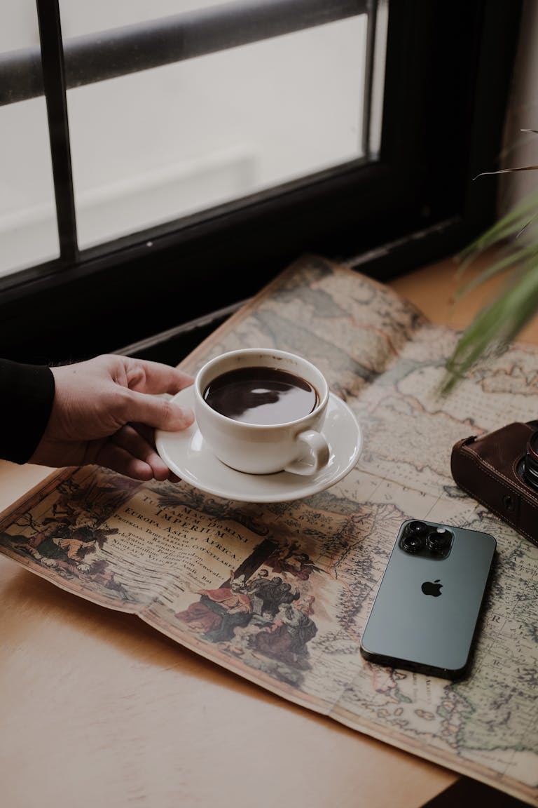 A person setting their phone face down on a table beside a journal and a cup of tea.