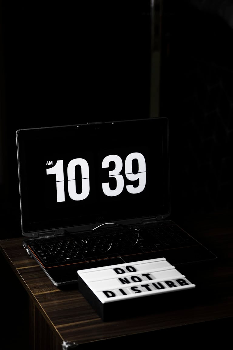 A peaceful workspace with a clock, notebook, and a "Do Not Disturb" sign, surrounded by blurred social media icons fading away.