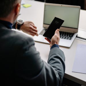 A person working at a desk with a to-do list, laptop, and a clock showing time management in action.