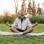 A person relaxing in a park with eyes closed, sunlight on their face, symbolizing a moment of peaceful reflection.