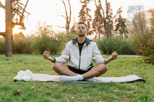 A person relaxing in a park with eyes closed, sunlight on their face, symbolizing a moment of peaceful reflection.